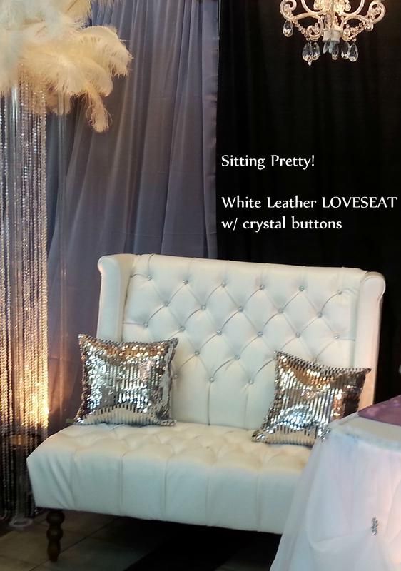 A white leather loveseat with crystal buttons