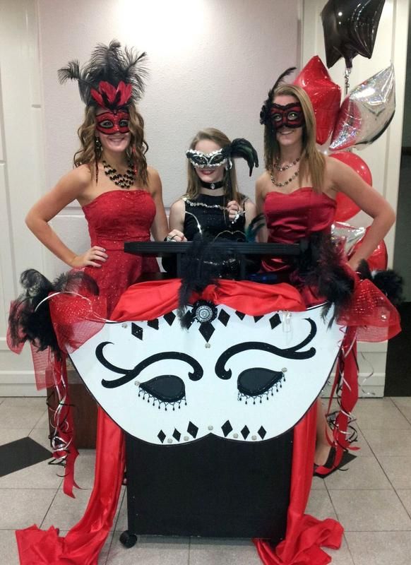 Three women wearing masks are standing next to a table with a mask on it