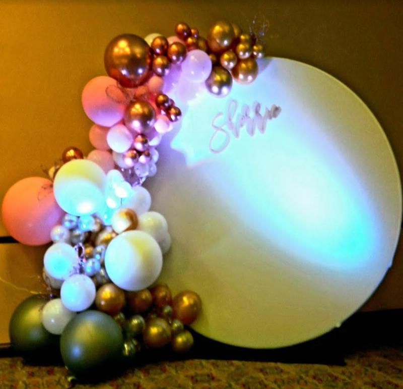 A sign with the name sally written on it is surrounded by balloons