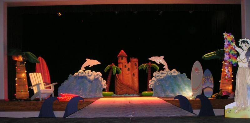 A stage with a castle , dolphins , palm trees and surfboards on it
