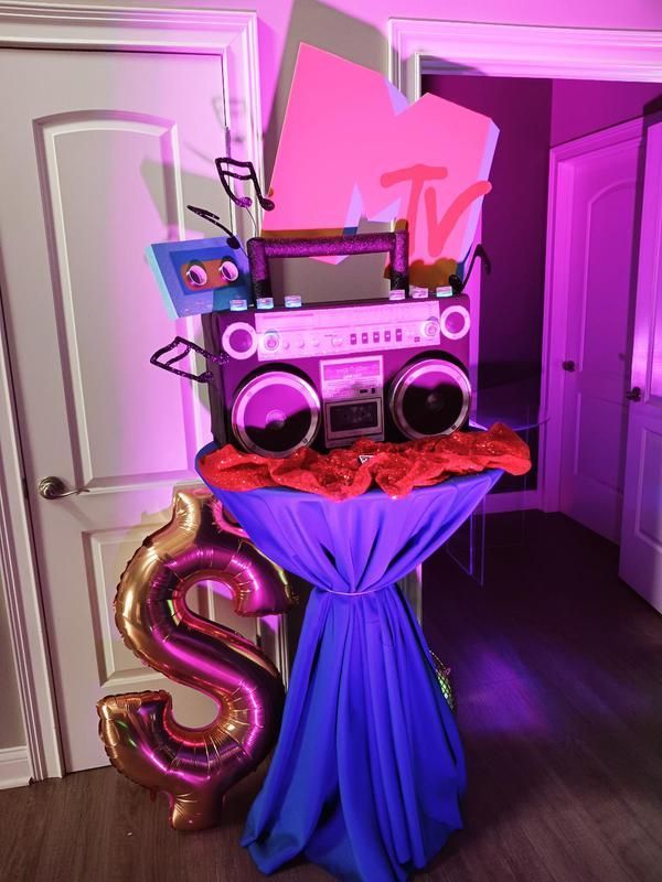 A table with a boombox and balloons on it in a room.