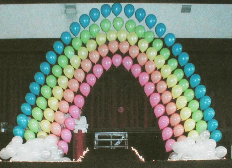 A bunch of balloons arranged in the shape of a rainbow