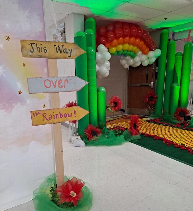 A room decorated with balloons and flowers and a sign that says this way over and rainbow.