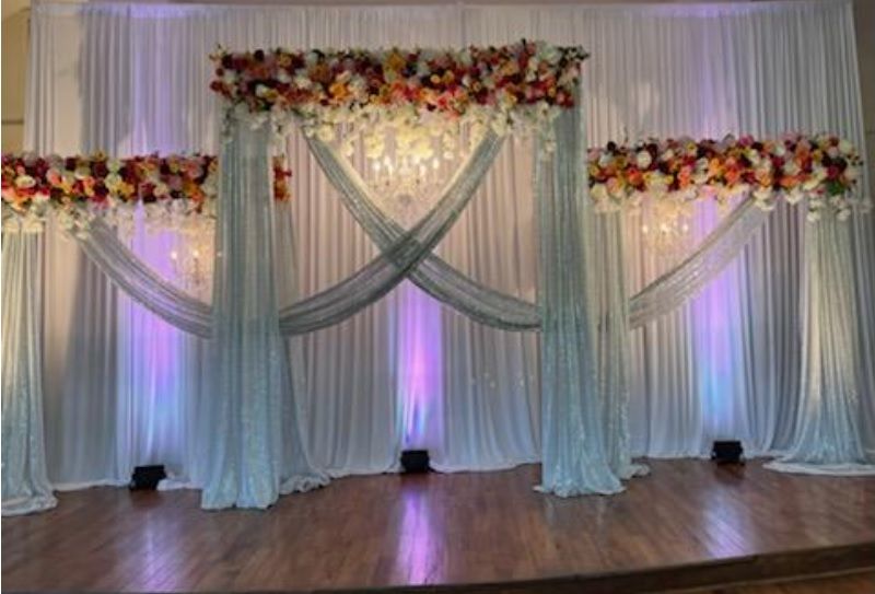A stage with a white curtain and flowers on it.