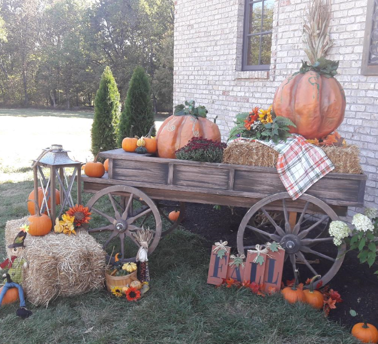 A wooden wagon filled with pumpkins and hay bales