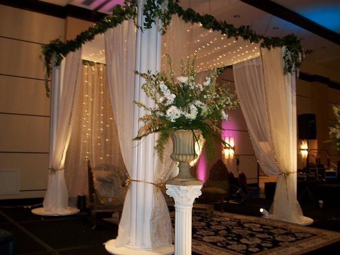 A white canopy with flowers in a vase on a pedestal