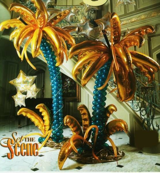 Two palm trees made out of balloons with the words set the scene below them