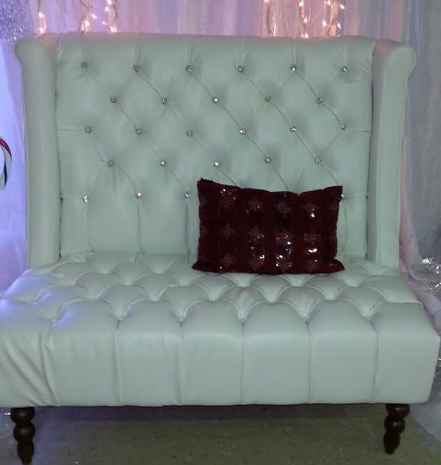 A white couch with a red pillow on it