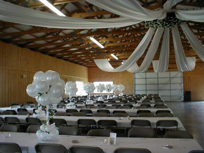 A large room with tables and chairs decorated with white balloons