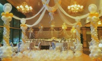 A room decorated with balloons and ribbons for a wedding reception.
