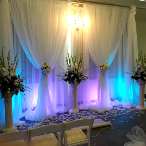 A room with white curtains and flowers in vases