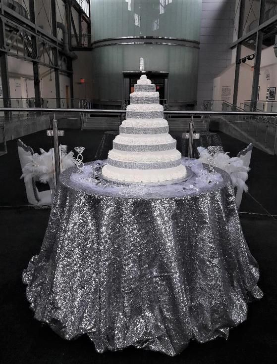 A wedding cake on a table with a silver table cloth