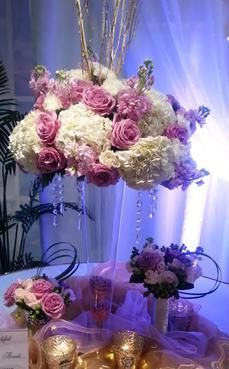 A table with a vase filled with pink and white flowers.