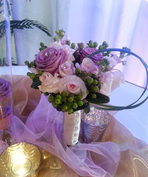 A bouquet of pink roses and green berries sits on a table