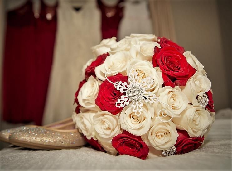 A bouquet of red and white roses is sitting next to a pair of shoes.