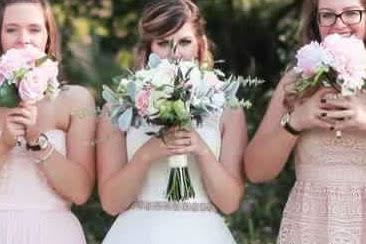 A bride and her bridesmaids are posing for a picture while holding bouquets of flowers.