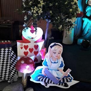 Alice in wonderland is sitting on a table reading a book.
