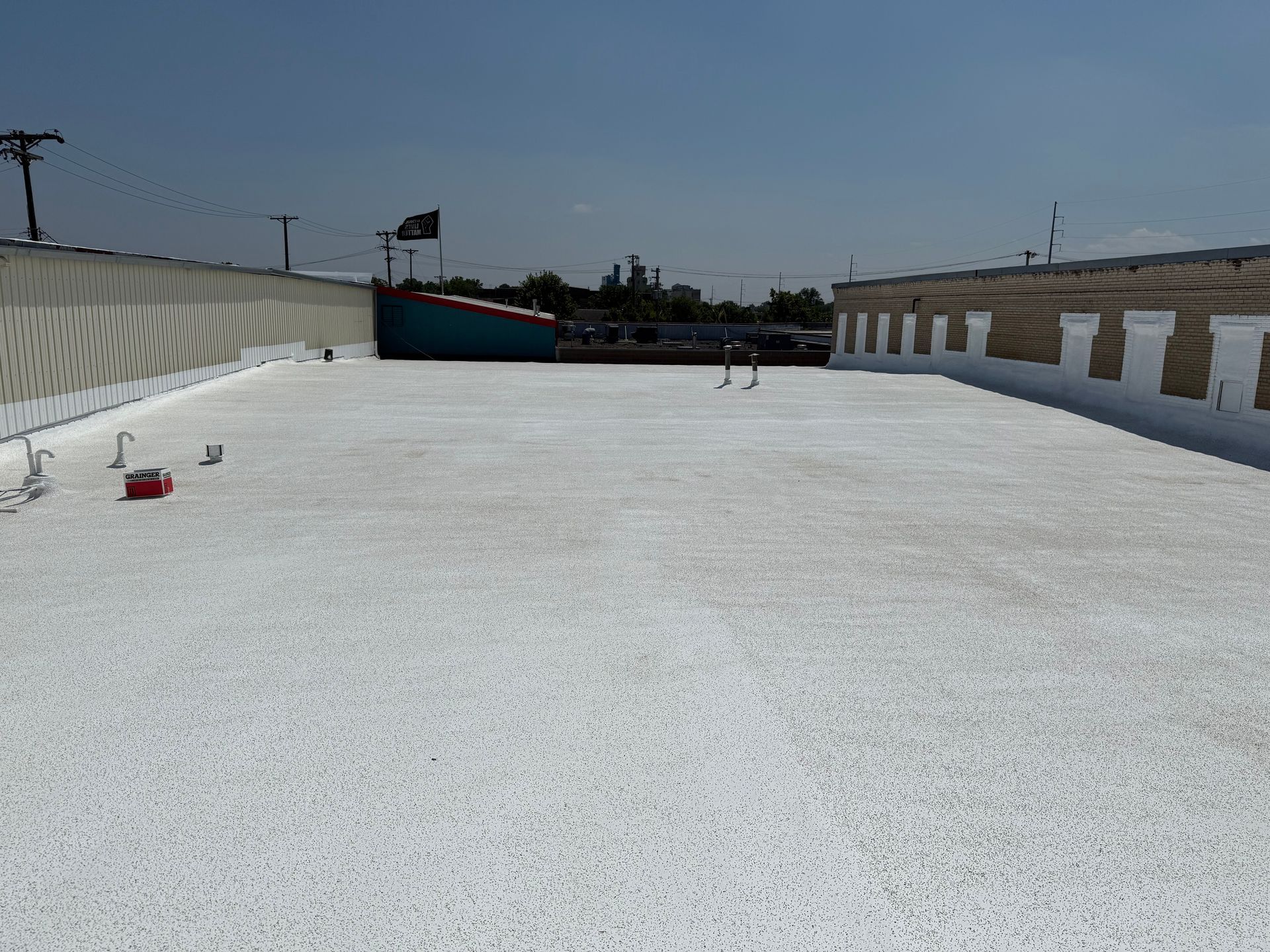 White-coated rooftop with a small ship, a black flag, and the sky in the background.