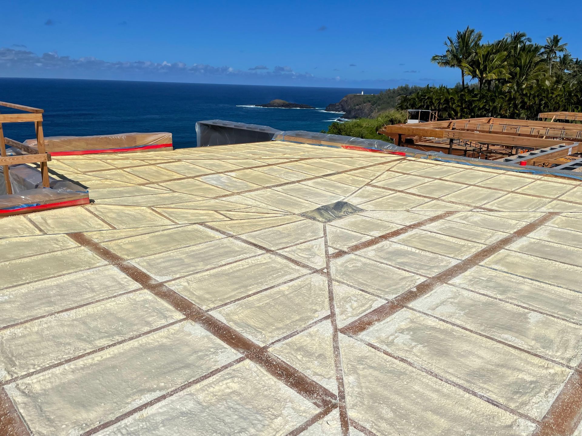Large sheets of drying salt, laid out on a roof with a scenic ocean view on a sunny day.