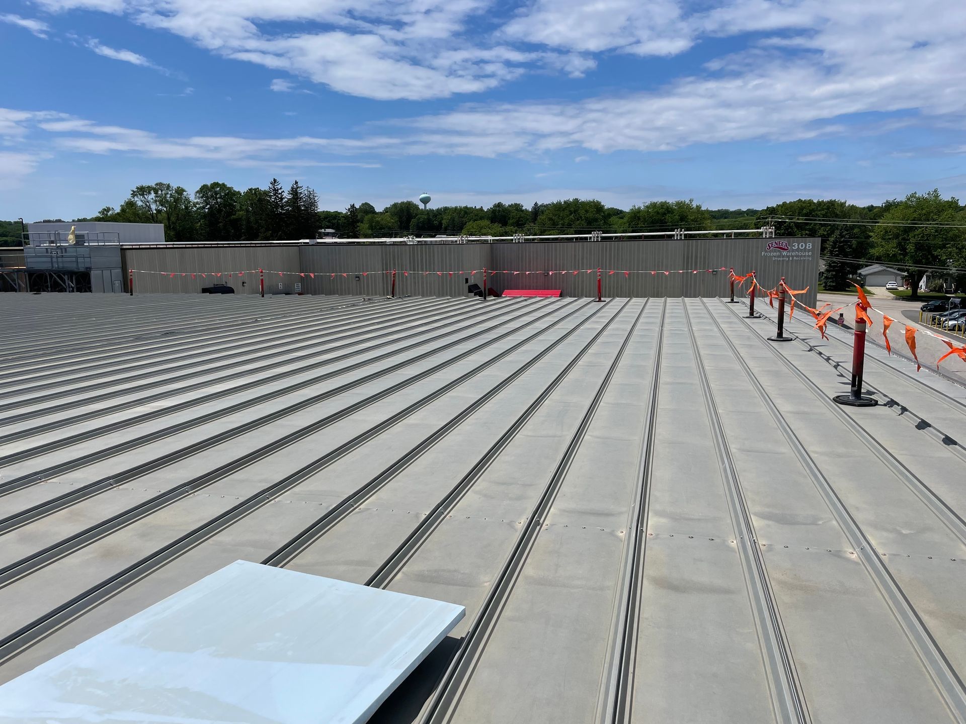 View of a flat commercial roof with metal beams. Safety flags and a skylight are visible.