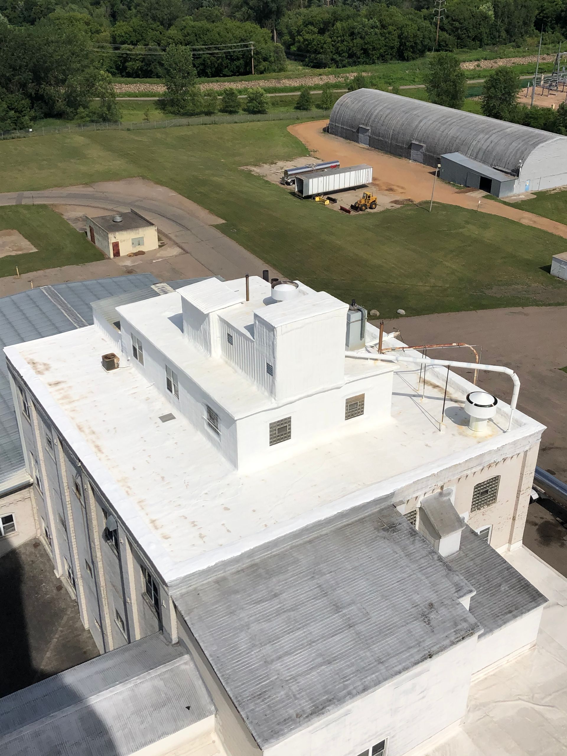 White building rooftop with vents and equipment, set in an industrial area.