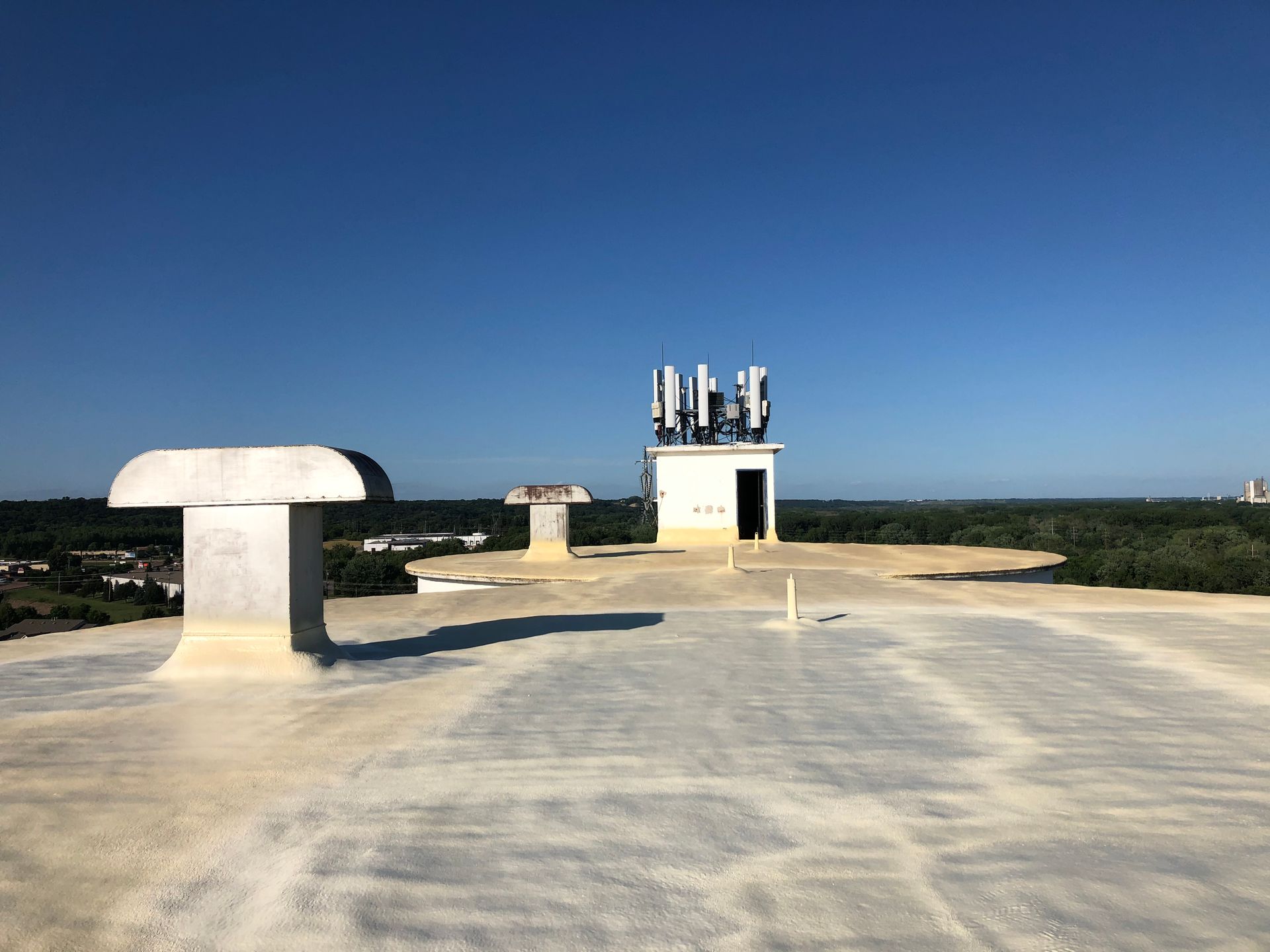 Rooftop view of communication equipment and vent against a clear blue sky.