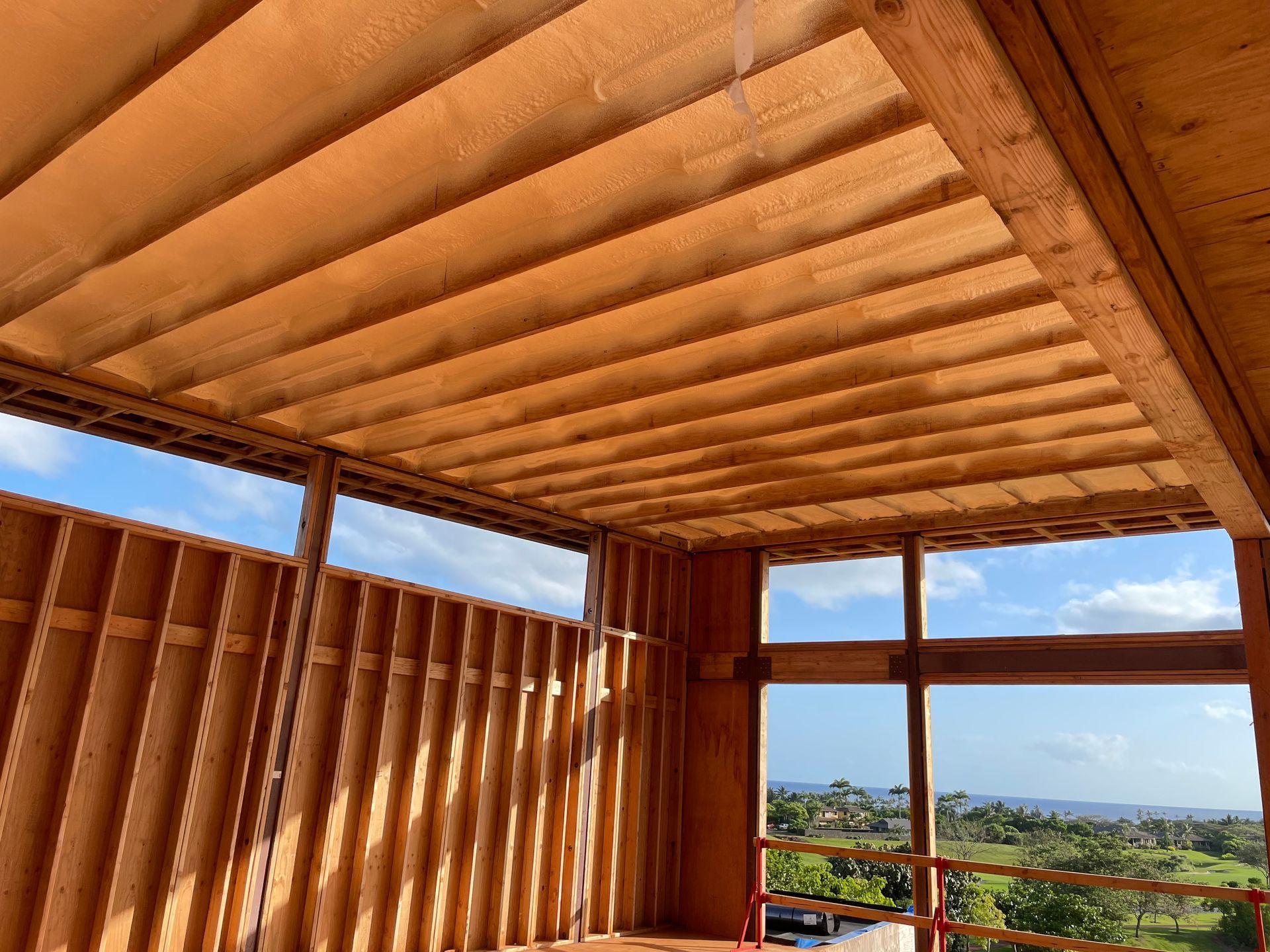 Interior view of a building under construction, featuring wooden beams and framing with a view of the outside.