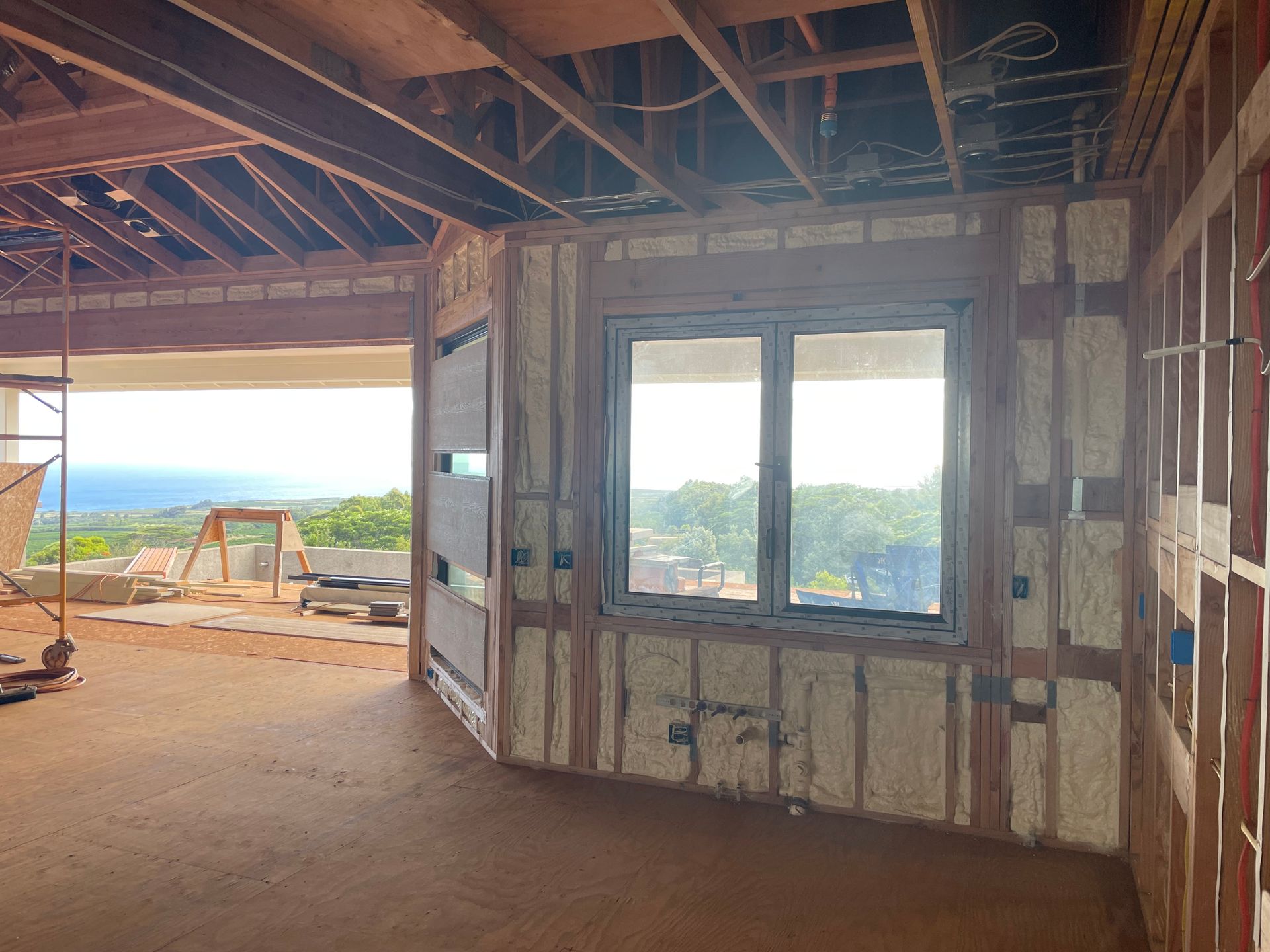 Interior of a building under construction, showing a window and spray foam insulation.