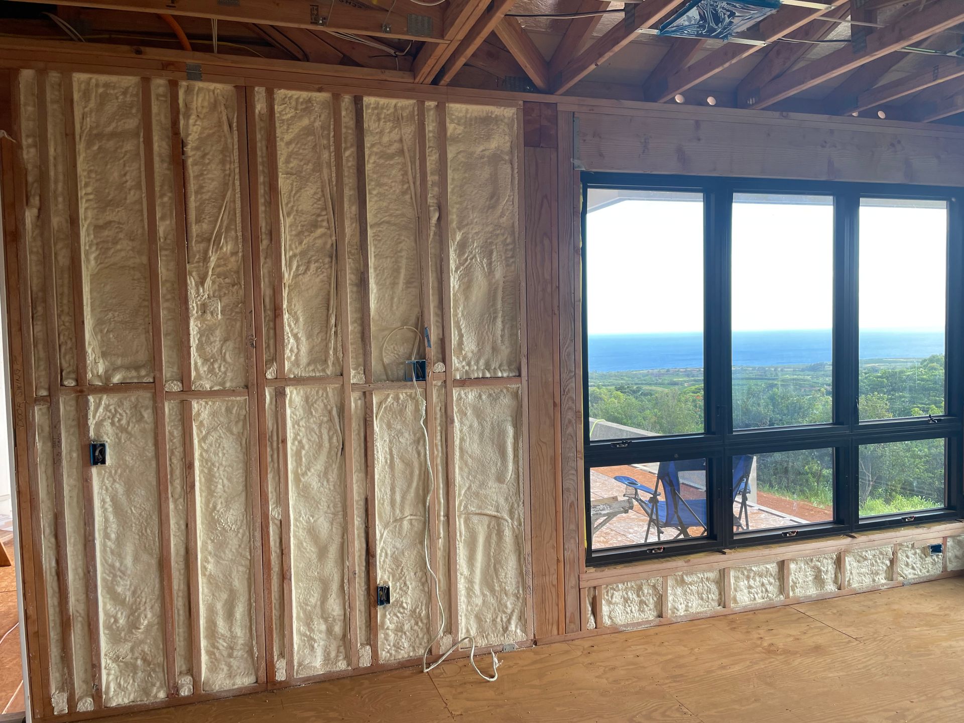 Interior view of a building under construction, spray foam insulation applied to wooden wall framing.