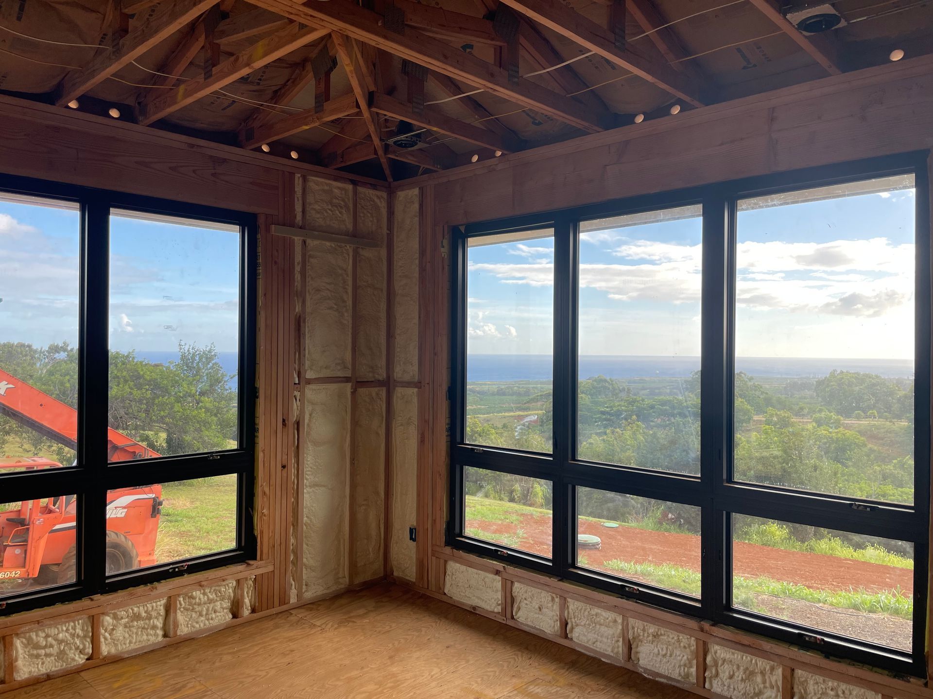 Interior of a room under construction with large black-framed windows overlooking a scenic landscape.