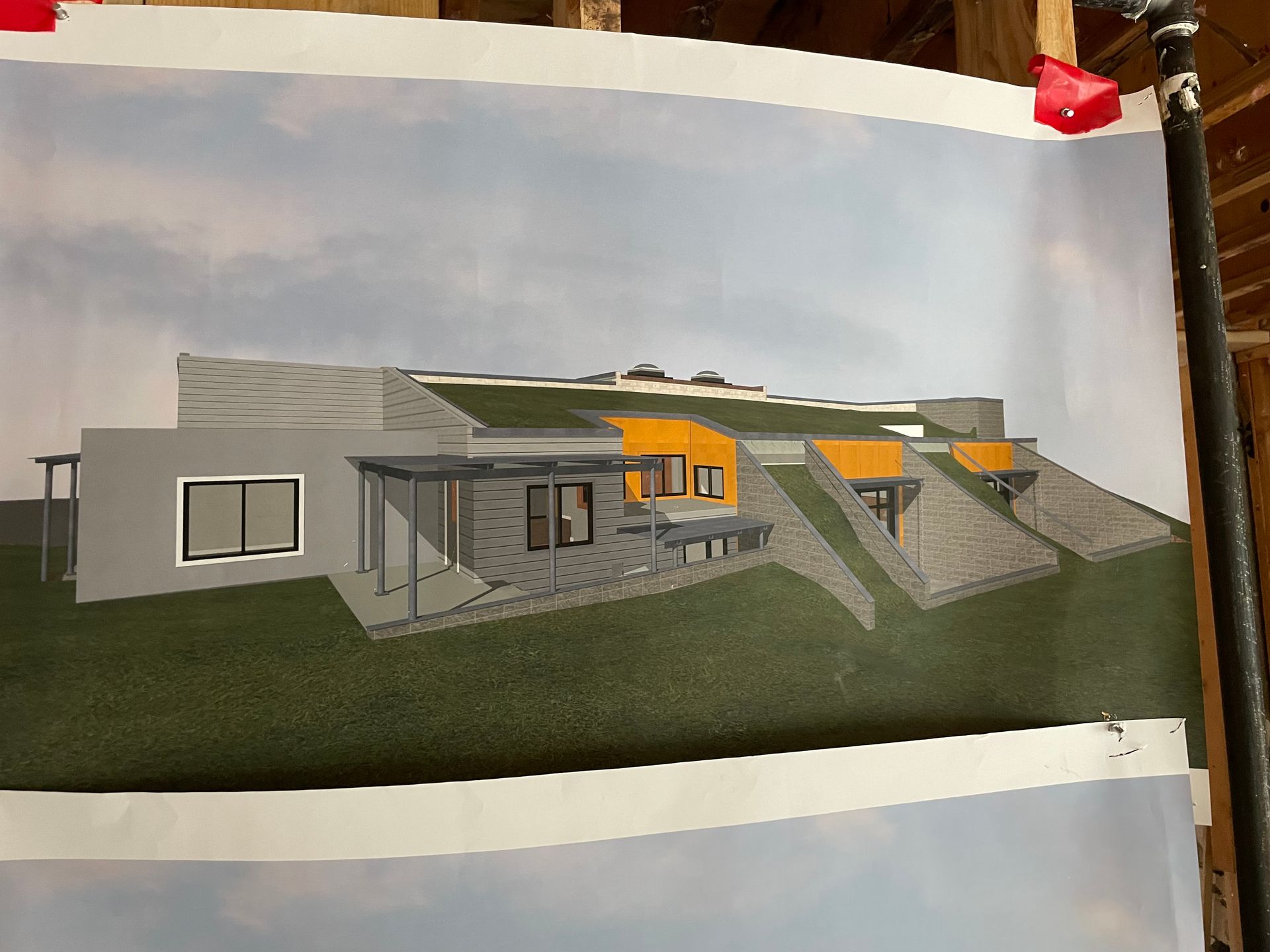 Architectural rendering of a modern home with a green roof, gray walls, and orange accents, set on a hillside.