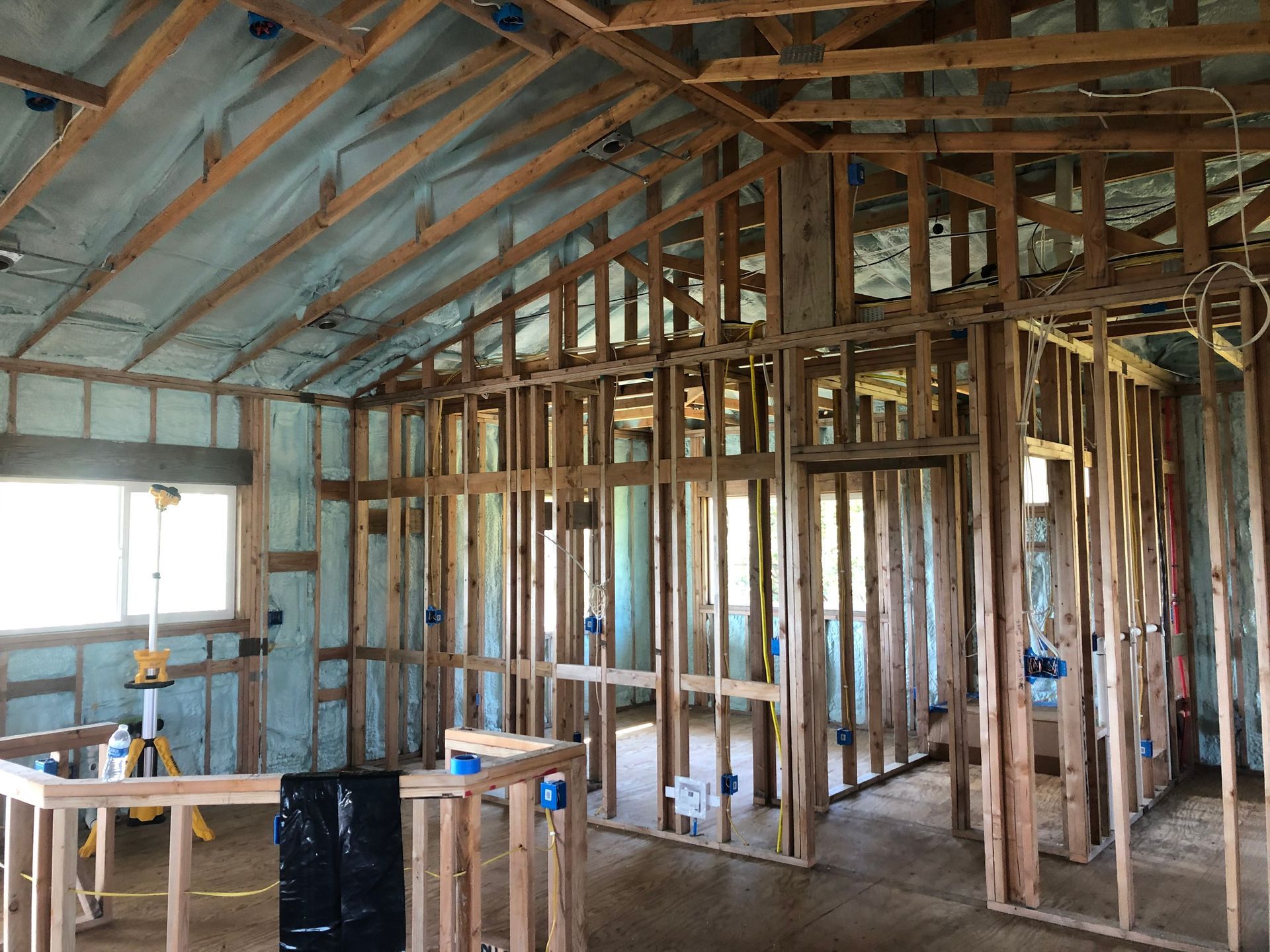 Interior of a building under construction, wooden frames, blue electrical boxes, spray foam insulation.