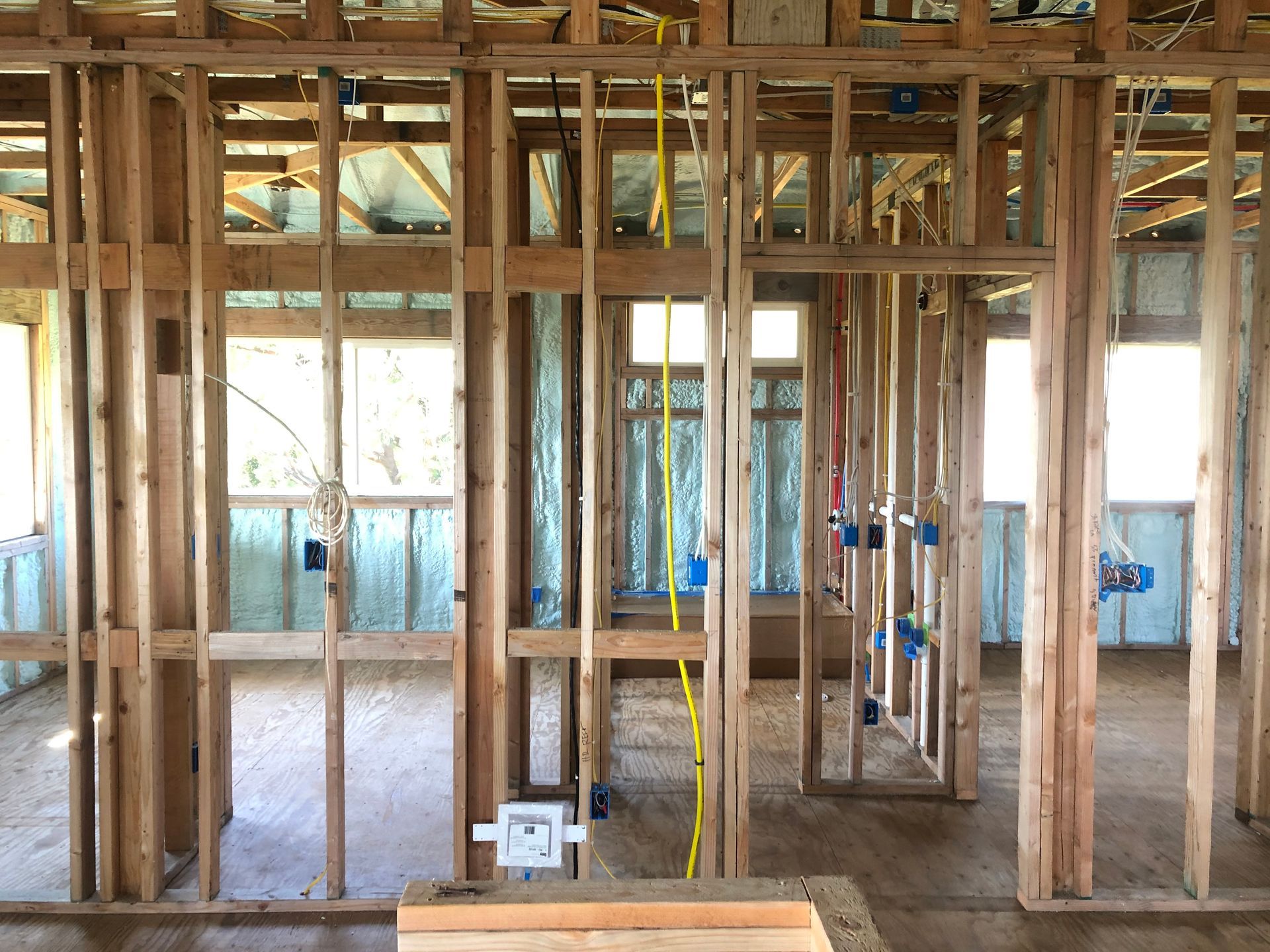 Interior of a building under construction, showing wooden framing, electrical wiring, and blue electrical boxes.