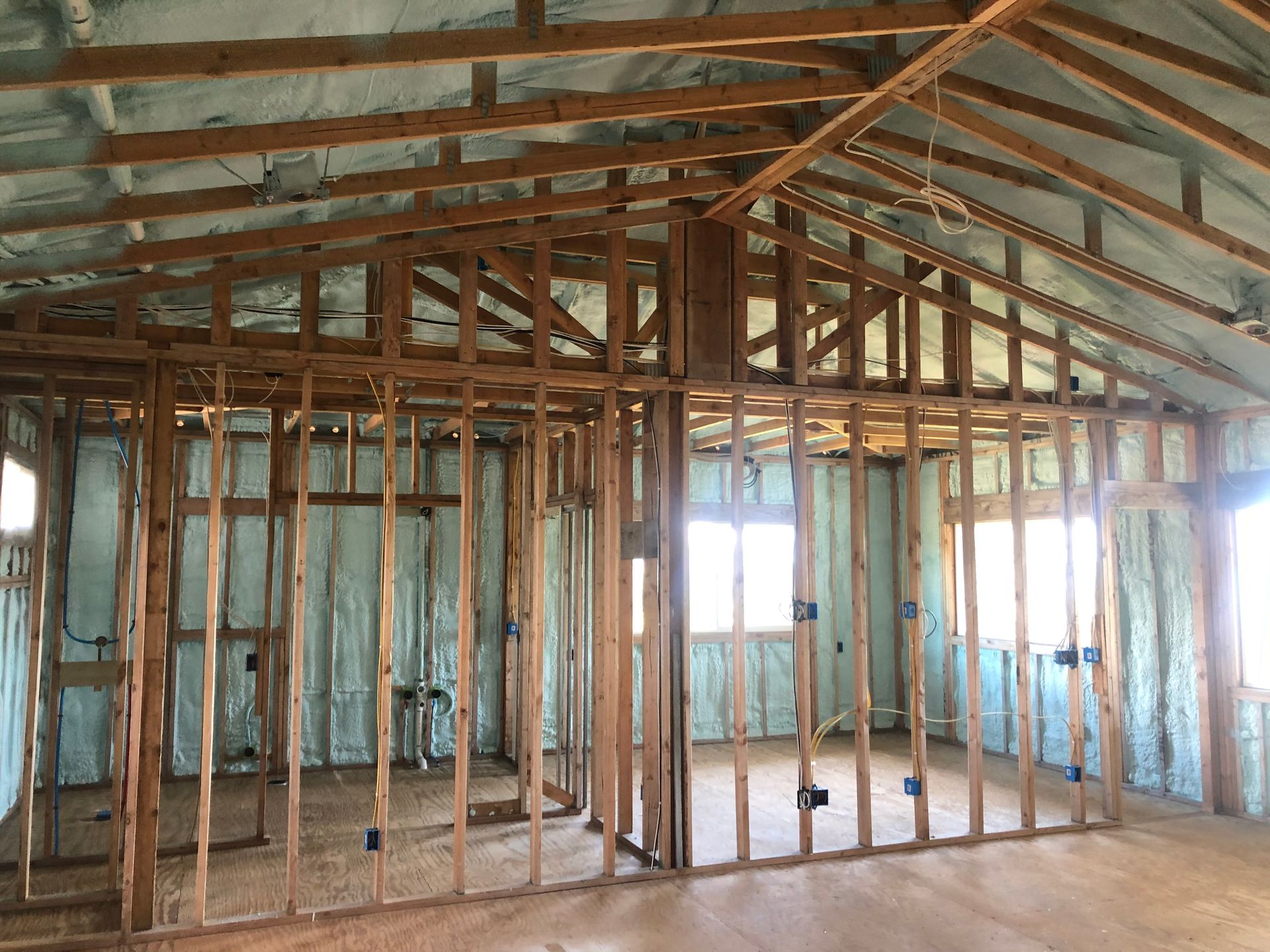Interior view of a building frame with insulation sprayed on the walls and ceiling.