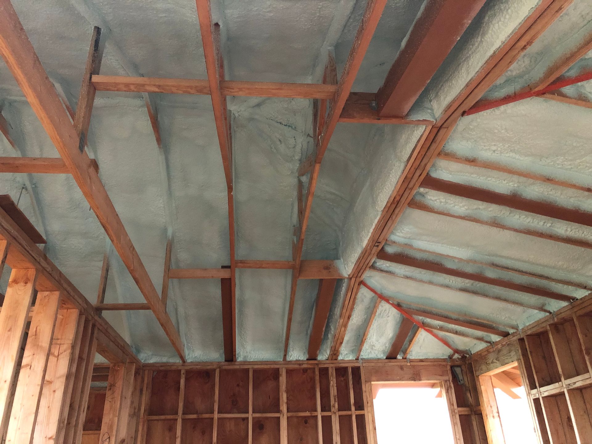 Interior view of a building under construction, spray foam insulation applied to the rafters and ceiling.