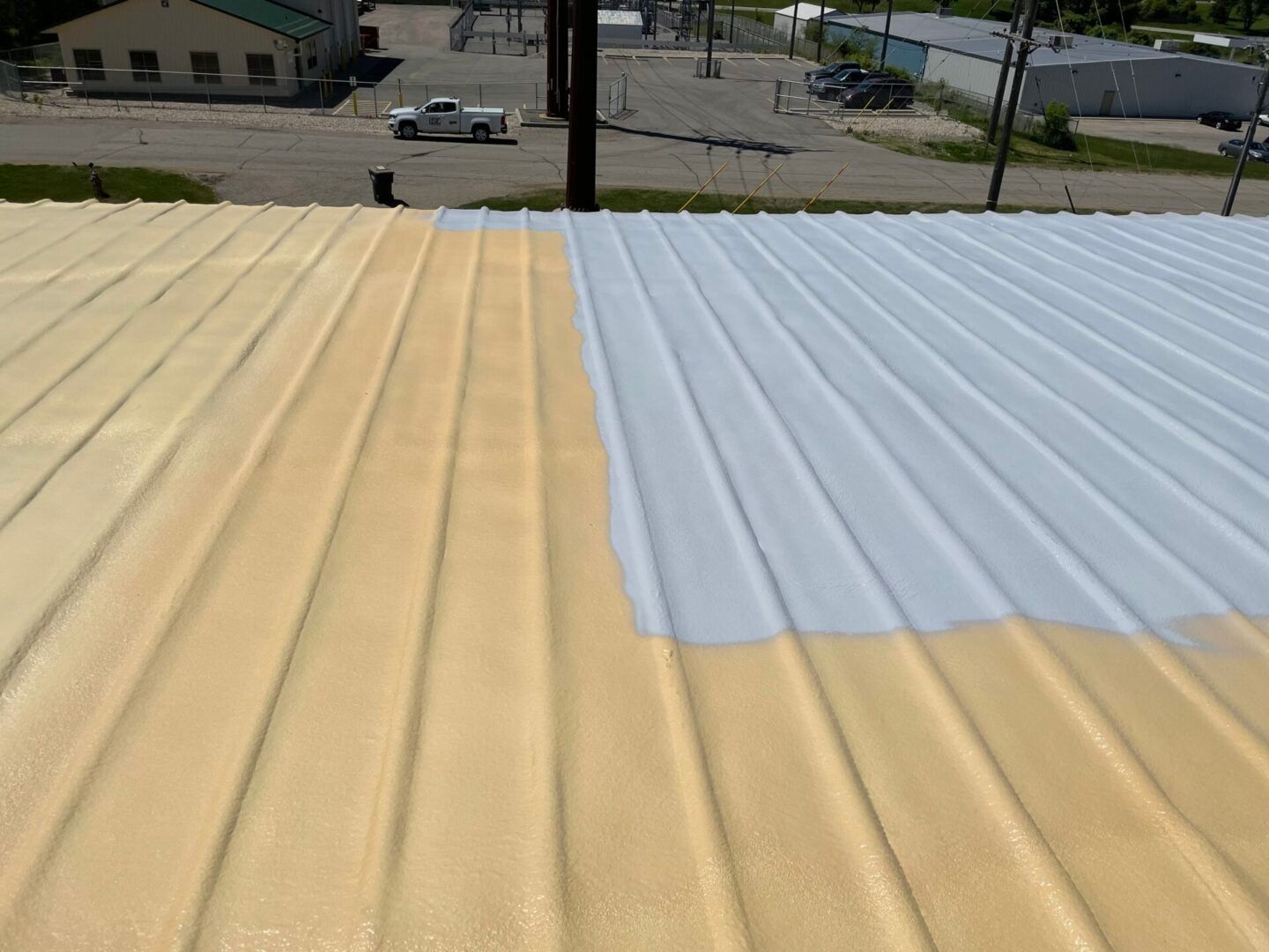 Metal roof partially painted yellow and white, in an industrial setting.