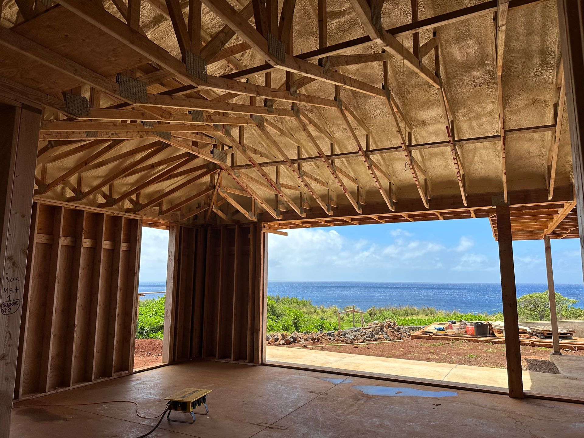 Interior view of a building under construction, overlooking the ocean through an open doorway.