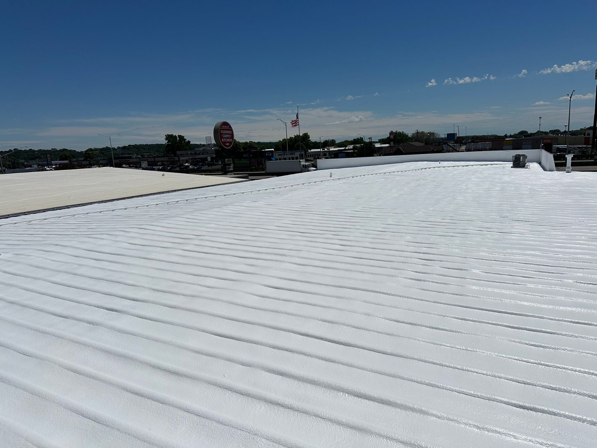 White, textured rooftop with ridged surface under a bright blue sky.