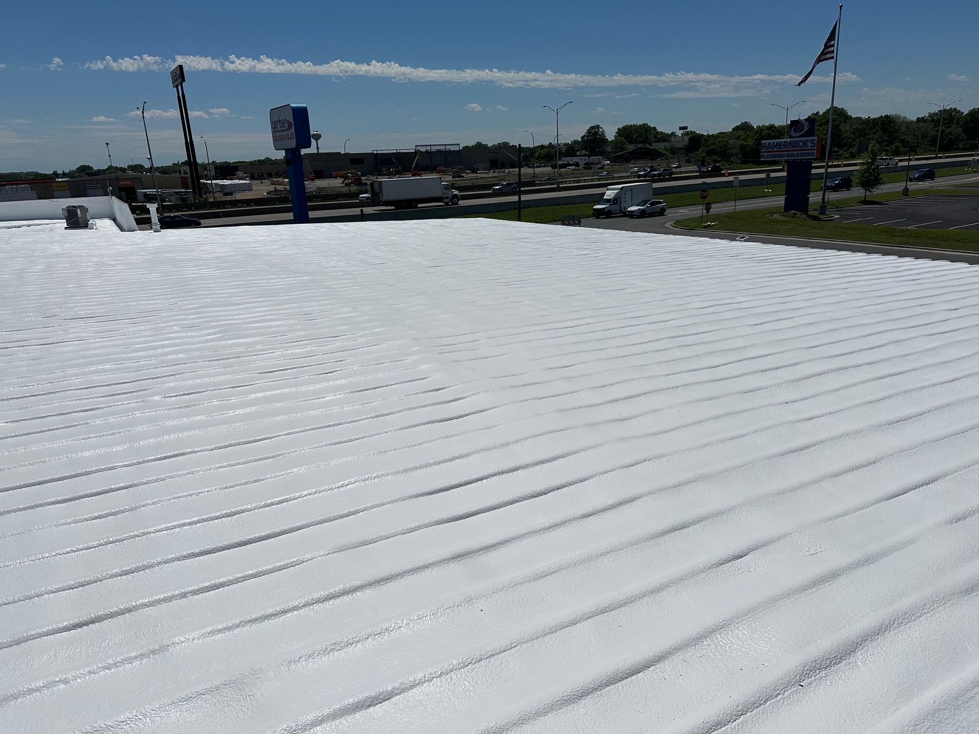 White, ridged roof of a building with a blue sky background and a fast food restaurant sign.