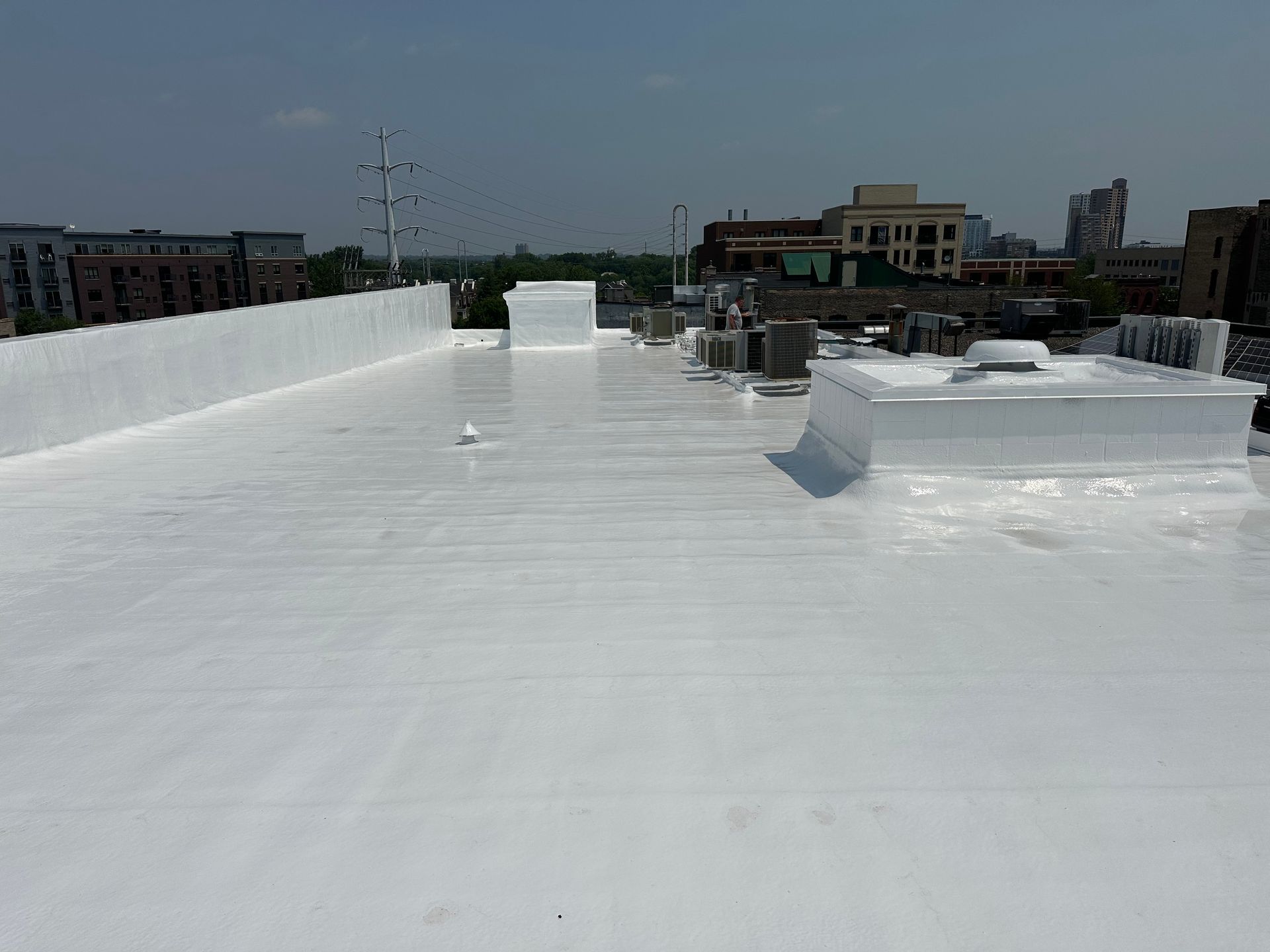Flat white roof with city skyline in the background.