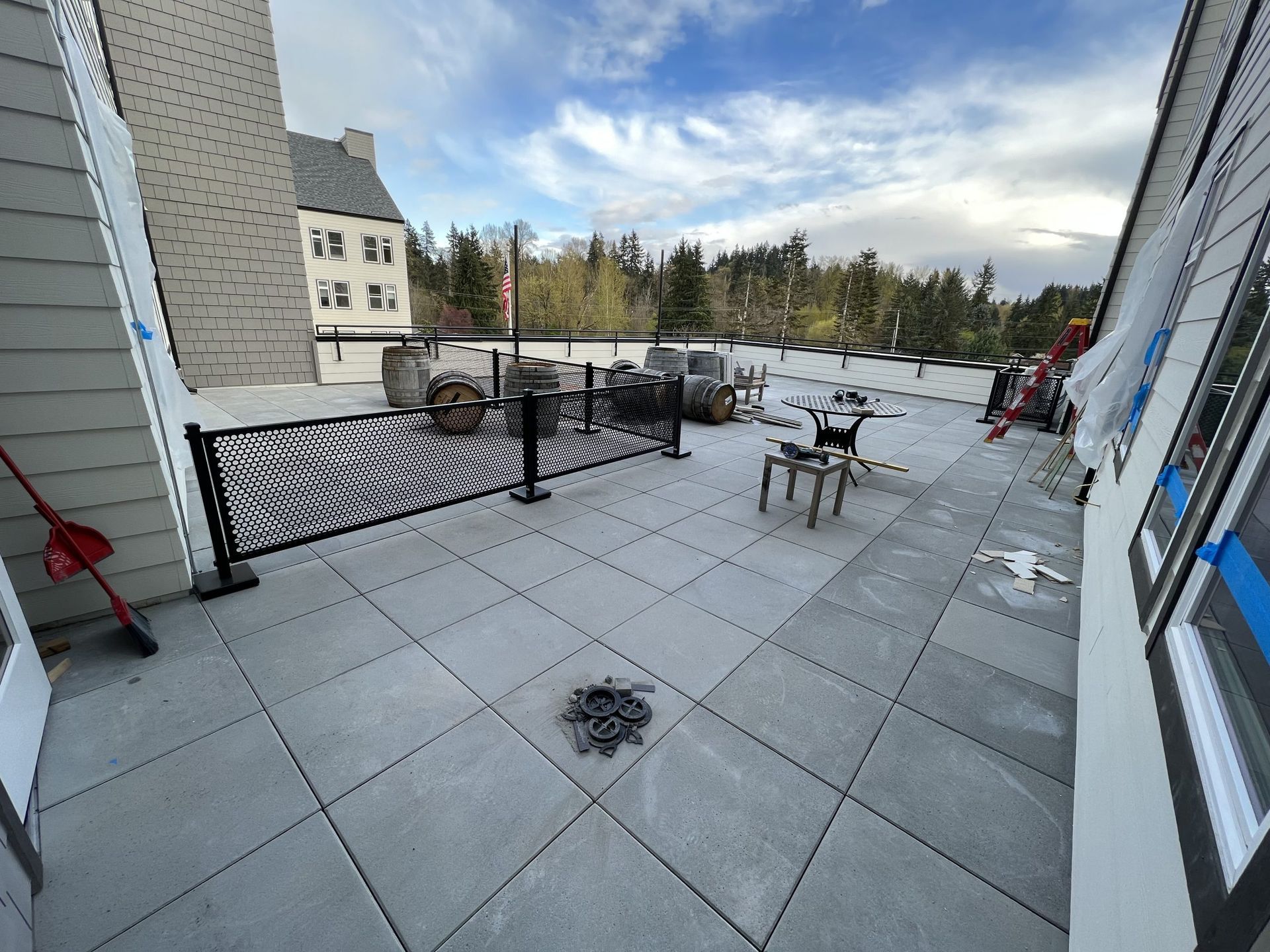 A patio with a fence and chairs is being built on the roof of a building in Monroe, WA.