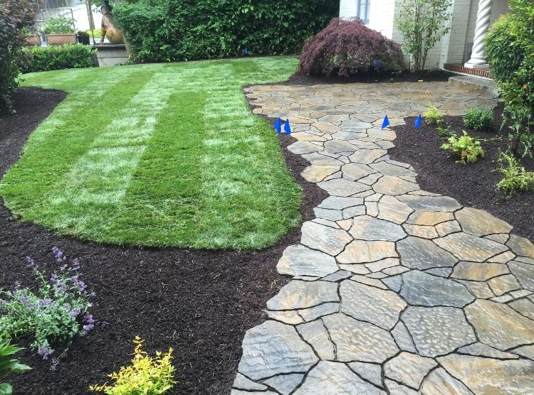 A stone walkway leading to a lush green lawn in Monroe, WA.