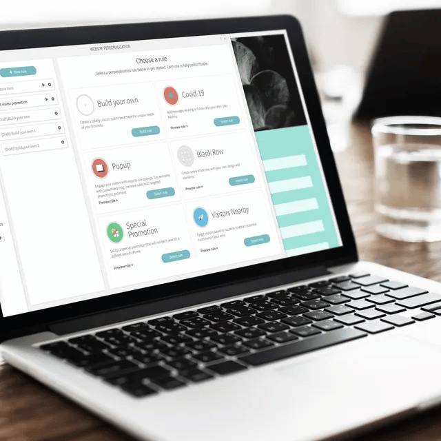Laptop displaying a user interface with progress trackers and buttons on a wooden table.
