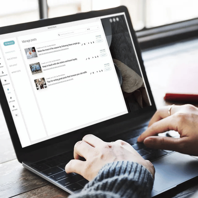 Person typing on laptop, viewing a webpage with a list of items.