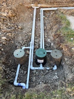 White PVC sprinkler valve system installed underground with wiring visible.