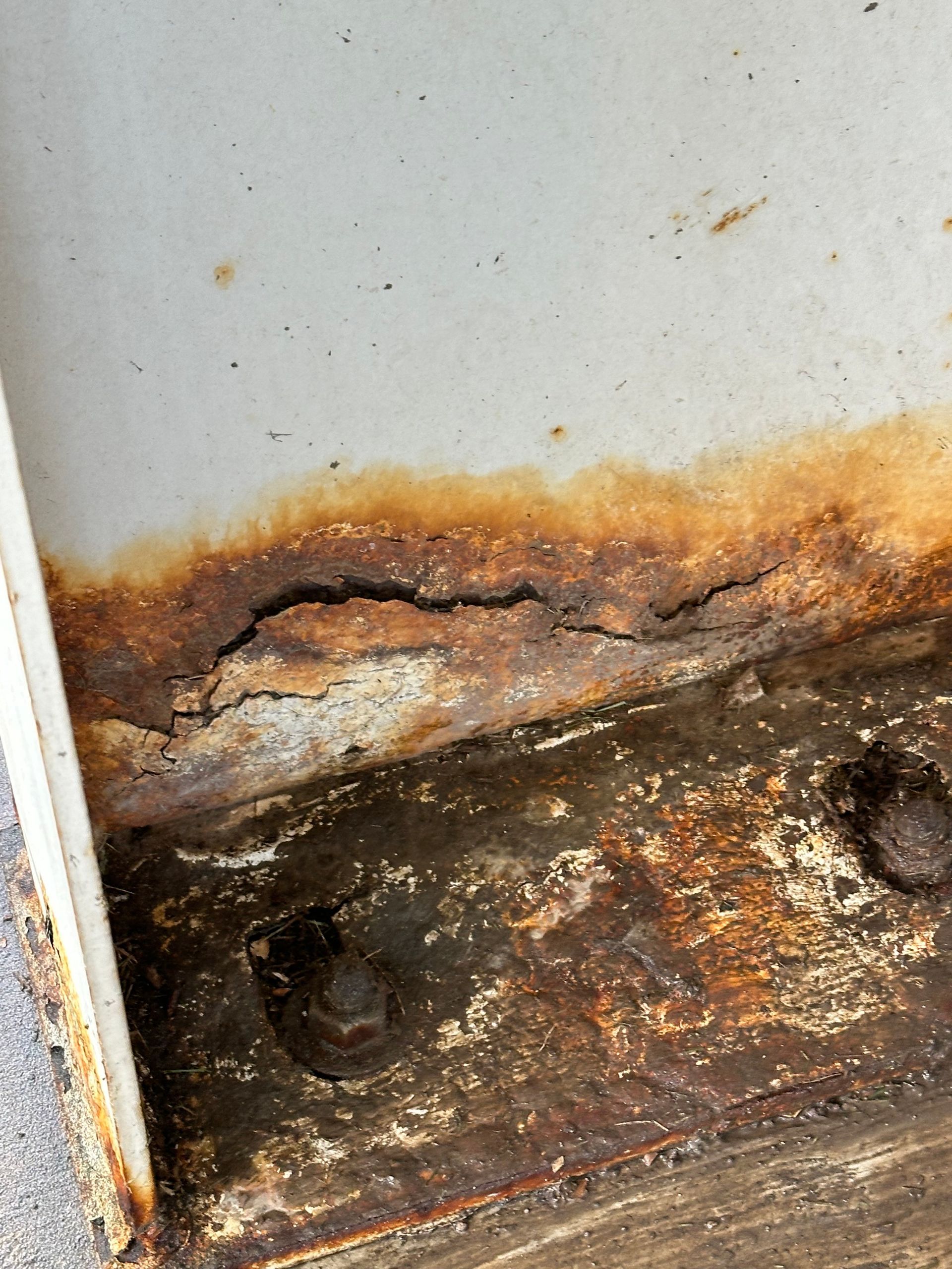 Severe rust and corrosion on metal structure, with visible flaking paint and discoloration.