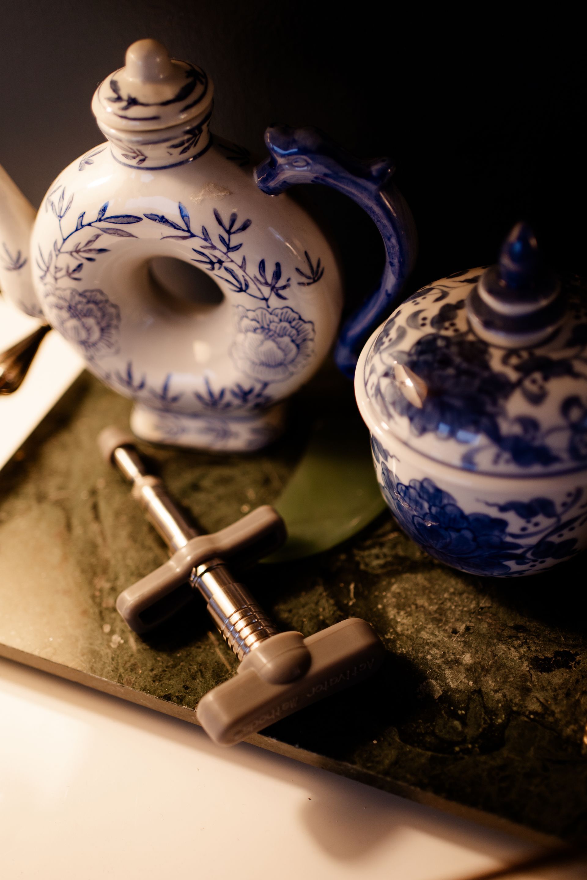 Blue-and-white porcelain jars and a metal cross on a dark surface