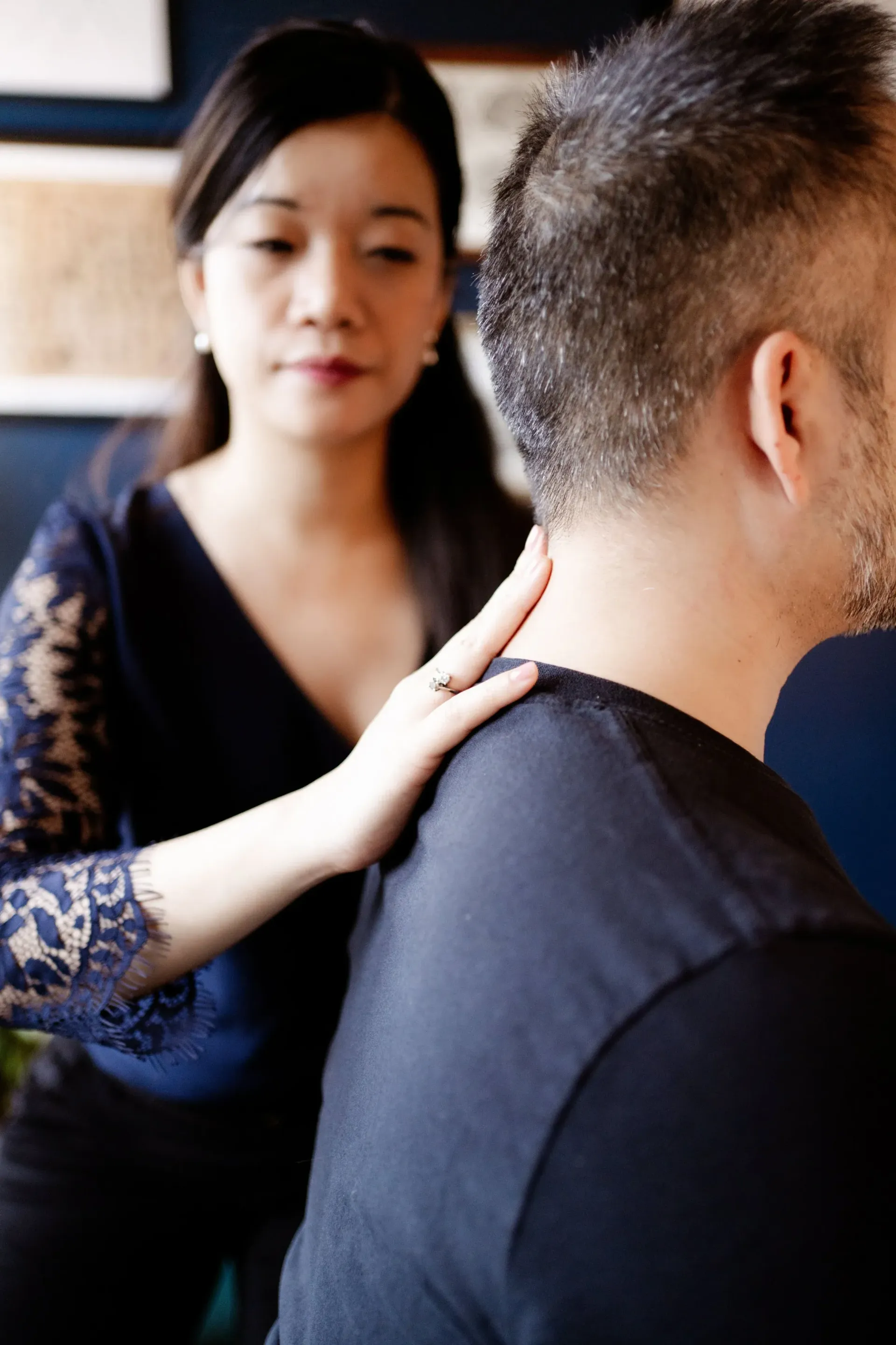 Woman giving a shoulder massage to a seated person indoors