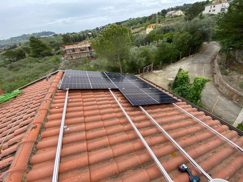 Una fila di pannelli solari è posizionata sopra un tetto di tegole.