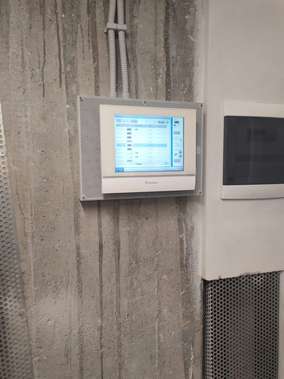 Un monitor bianco è montato su un muro di cemento.